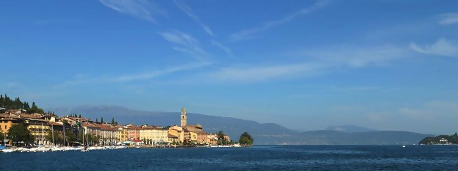 Trip Monaco beliebte Urlaubsziele am Gardasee -  Mit einer Fläche von 370 km² ist der Gardasee der größte See Italiens. Es liegt am Fuße der Alpen und erstreckt sich über drei Staaten: Lombardei, Venetien und Trentino. Die maximale Tiefe des Sees beträgt 346 m, er hat eine längliche Form und sein nördliches Ende ist sehr schmal. Dort ist der See von den Bergen der Gruppo di Baldo umgeben. Du trittst aus deinem gemütlichen Hotelzimmer und es begrüßt dich die warme italienische Sonne. Du blickst auf den atemberaubenden Gardasee, der in zahlreichen Blautönen schimmert - von tiefem Dunkelblau bis zu funkelndem Türkis. Majestätische Berge umgeben dich, während die Brise sanft deine Haut streichelt und der Duft von blühenden Zitronenbäumen deine Nase kitzelt. Du schlenderst die malerischen, engen Gassen entlang, vorbei an farbenfrohen, blumengeschmückten Häusern. Vereinzelt unterbricht das fröhliche Lachen der Einheimischen die friedvolle Stille. Du fühlst dich wie in einem Traum, der nicht enden will. Jeder Schritt führt dich zu neuen Entdeckungen und Abenteuern. Du probierst die köstliche italienische Küche mit ihren frischen Zutaten und verführerischen Aromen. Die Sonne geht langsam unter und taucht den Himmel in ein leuchtendes Orange-rot - ein spektakulärer Anblick.